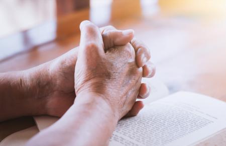 clasped hands on book