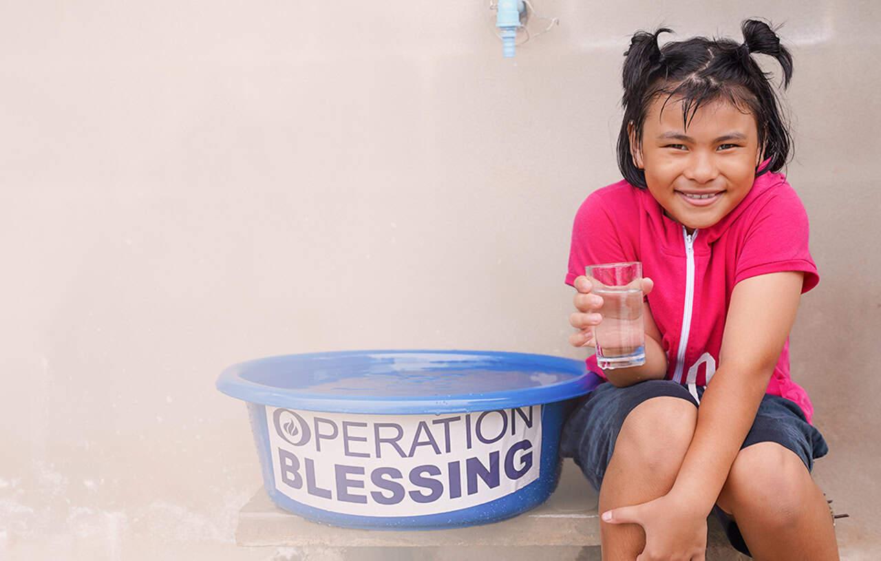 Girl with water from CBN's Operation Blessing