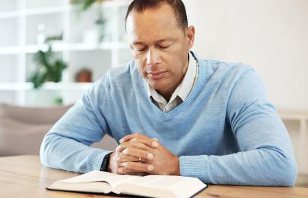 man reading Bible at a table