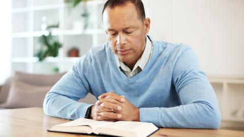 man reading Bible at a table