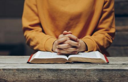 open bible clasped hands